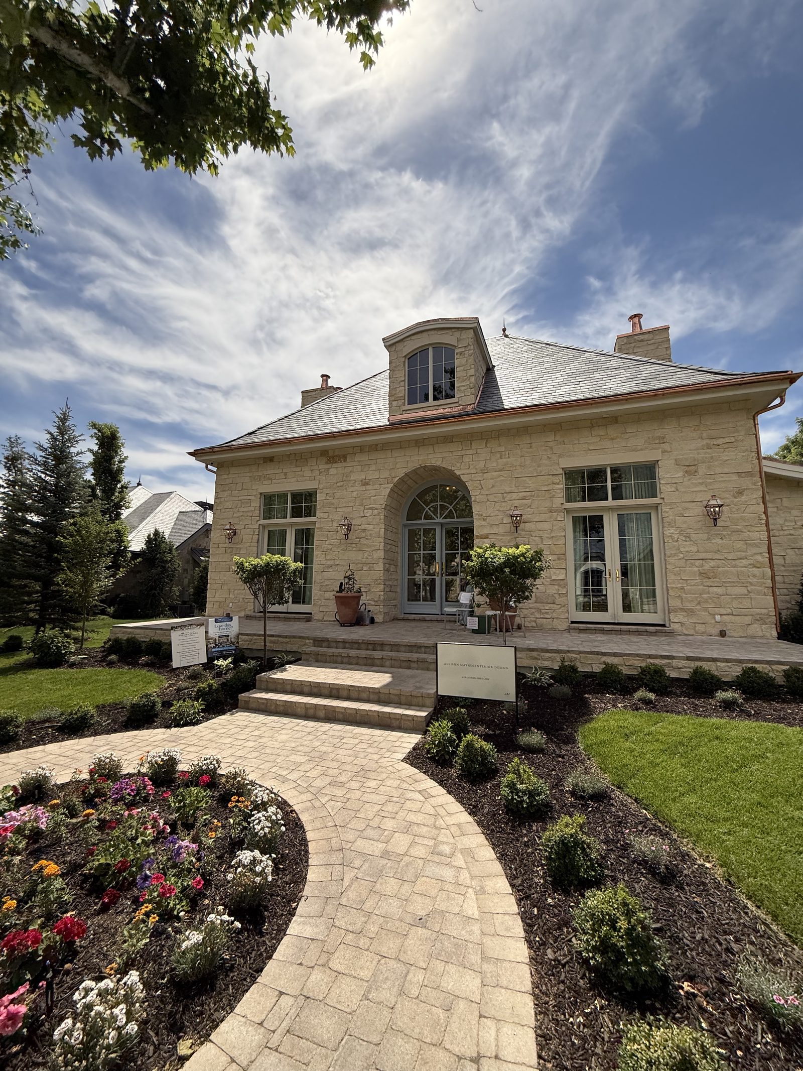 Stone exterior home with painted trim, dormers, and front door