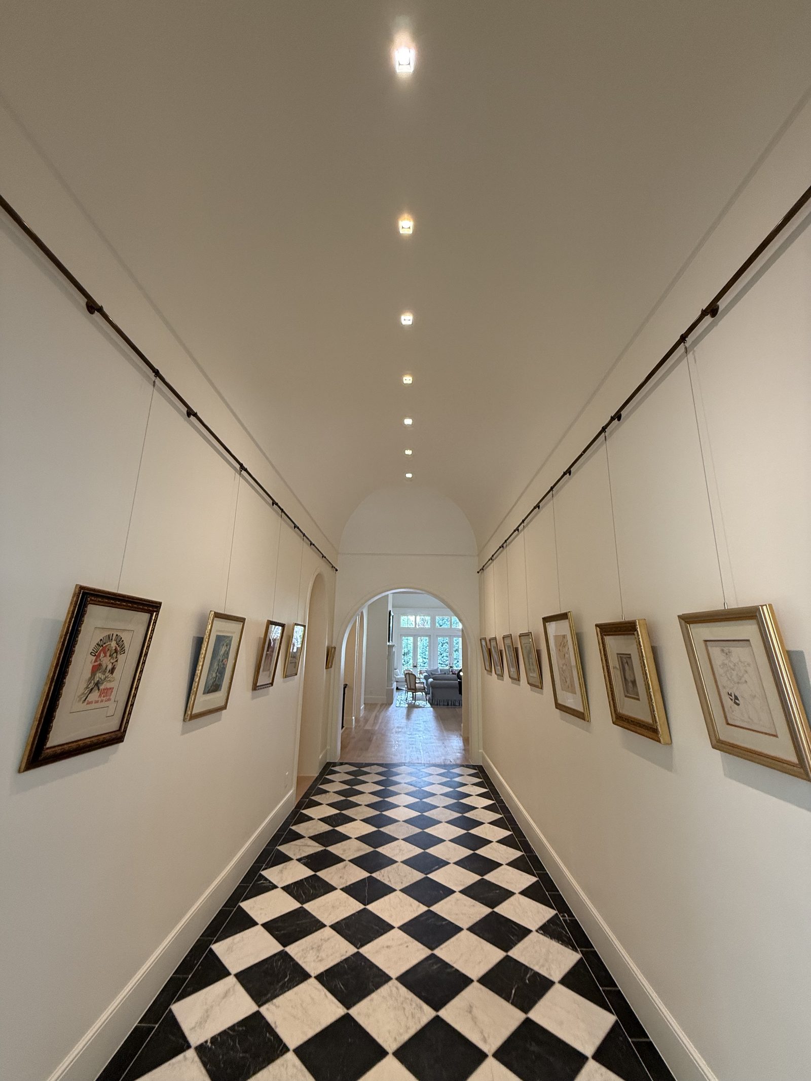 Long gallery hallway with checkered marble floor and white walls